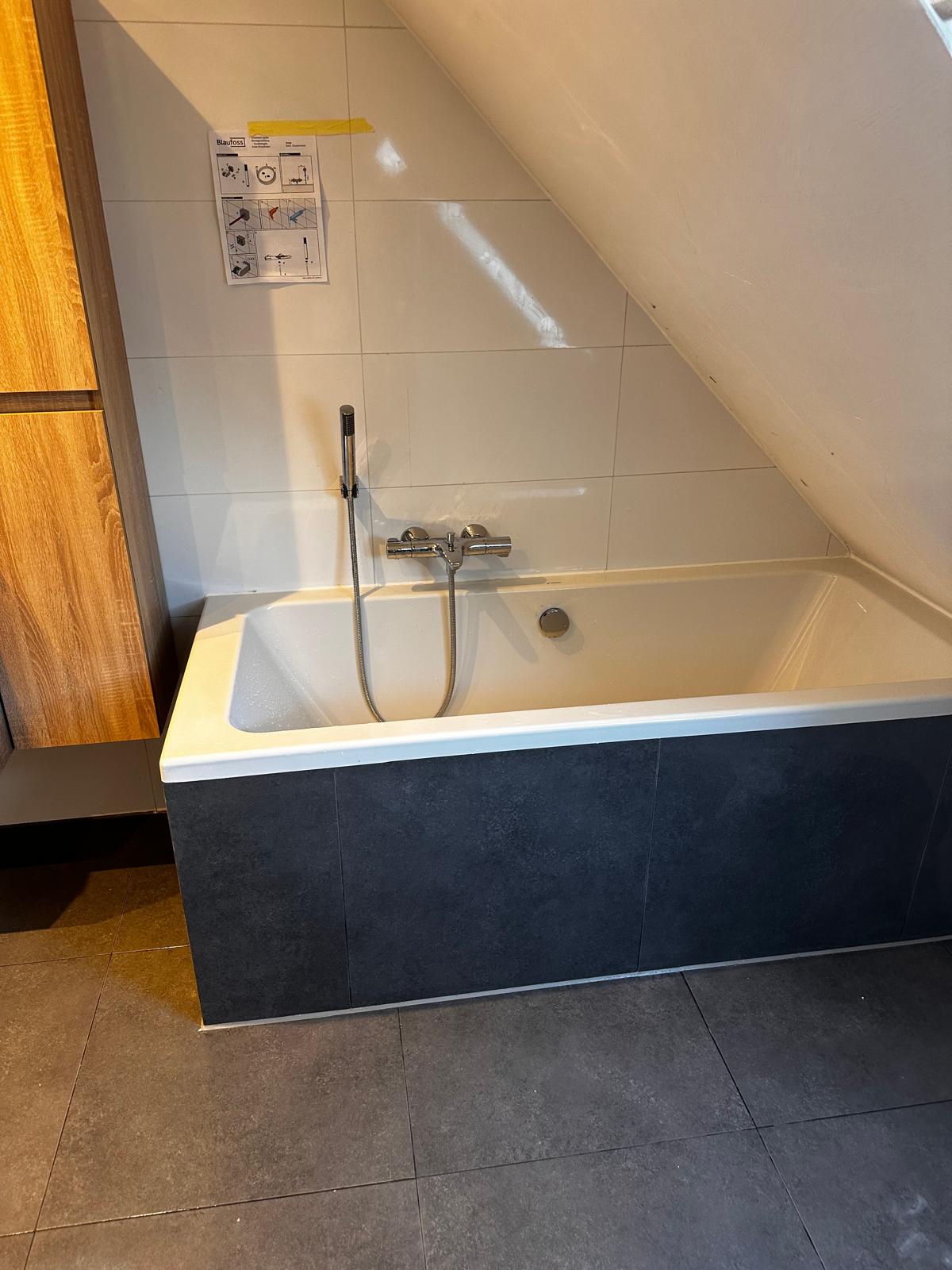 Badkamer onder schuin dak met ligbad en donkere badombouw